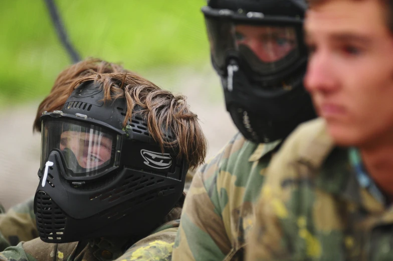 two men wearing paintball gear while sitting