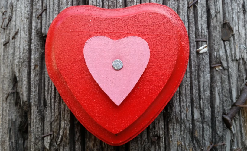 a red heart hanging on a wooden wall