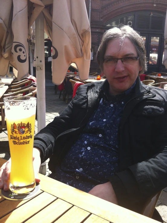 a person sitting at a wooden table with a mug of beer