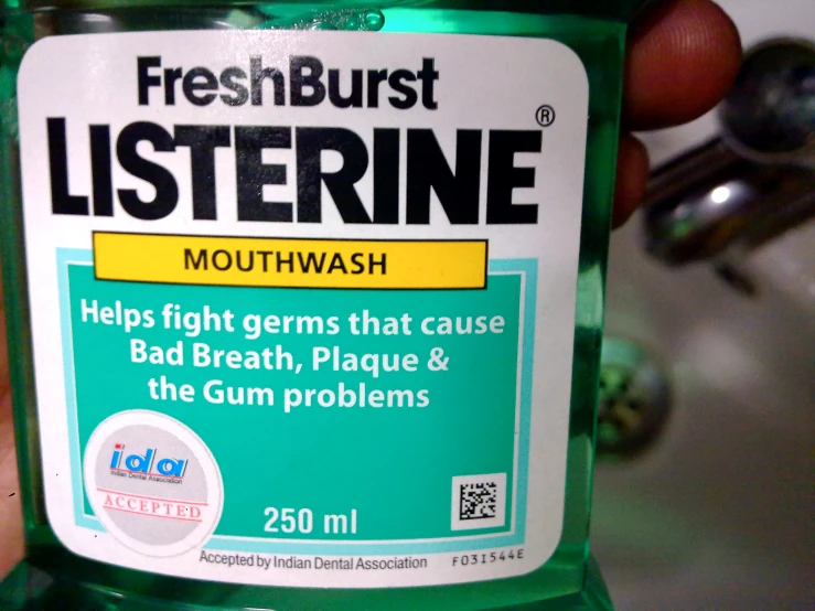 a person holding out the top of a bottle of mouthwash