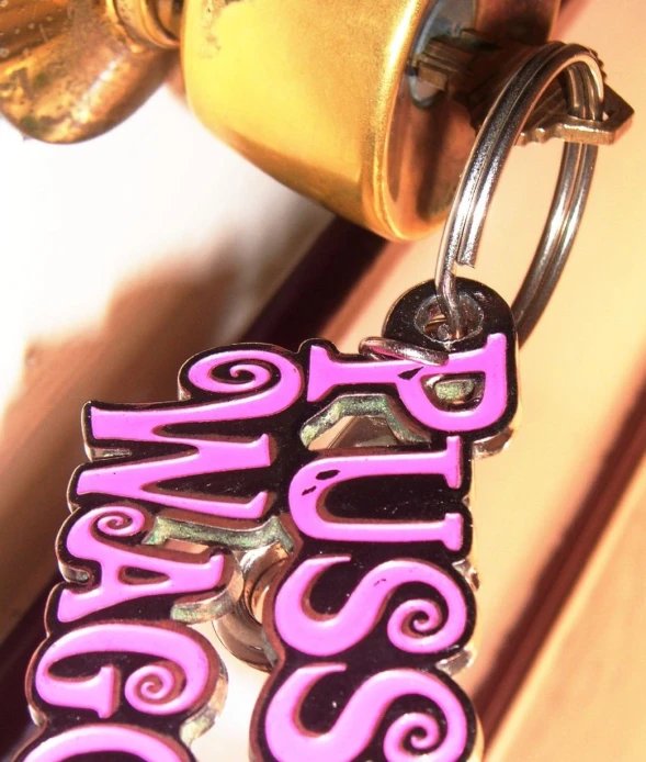 a purple and black logo hanging on a ss keychain