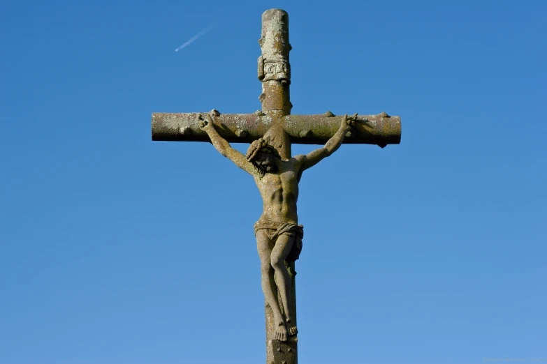 a wooden cross is shown with a blue sky in the background