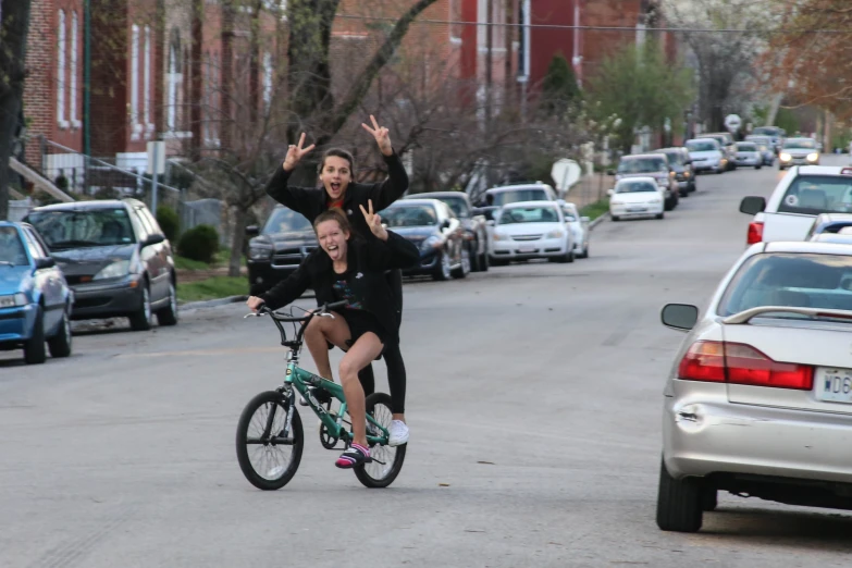 a woman on a bike and another woman raising her arms in the air