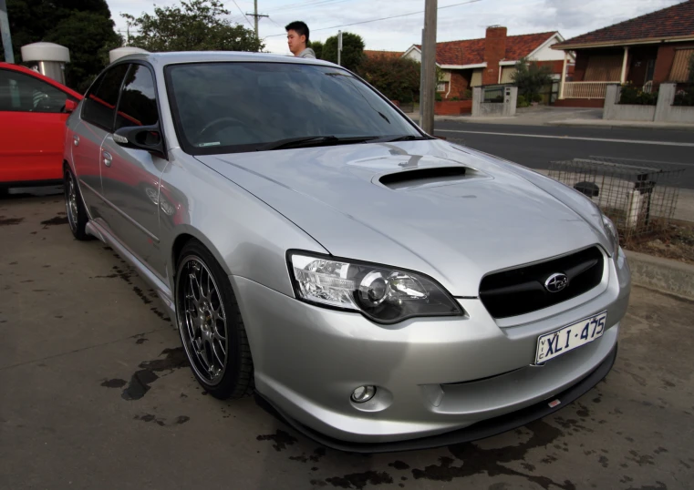 a silver subarunt parked next to a red car