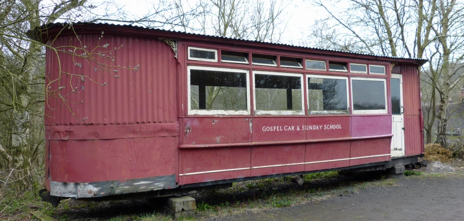 an old train car sitting in front of some trees