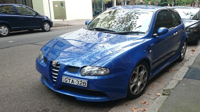 blue alfa coupe parked next to a curb on a city street