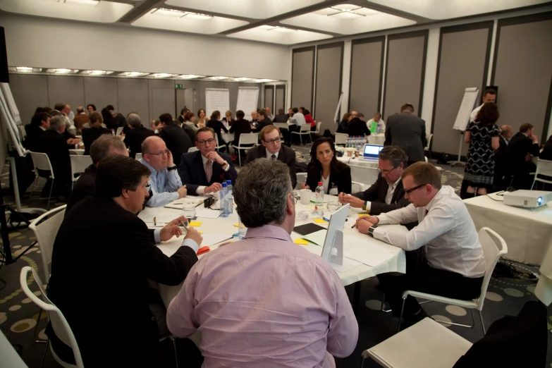 several people sitting at tables working on small laptops