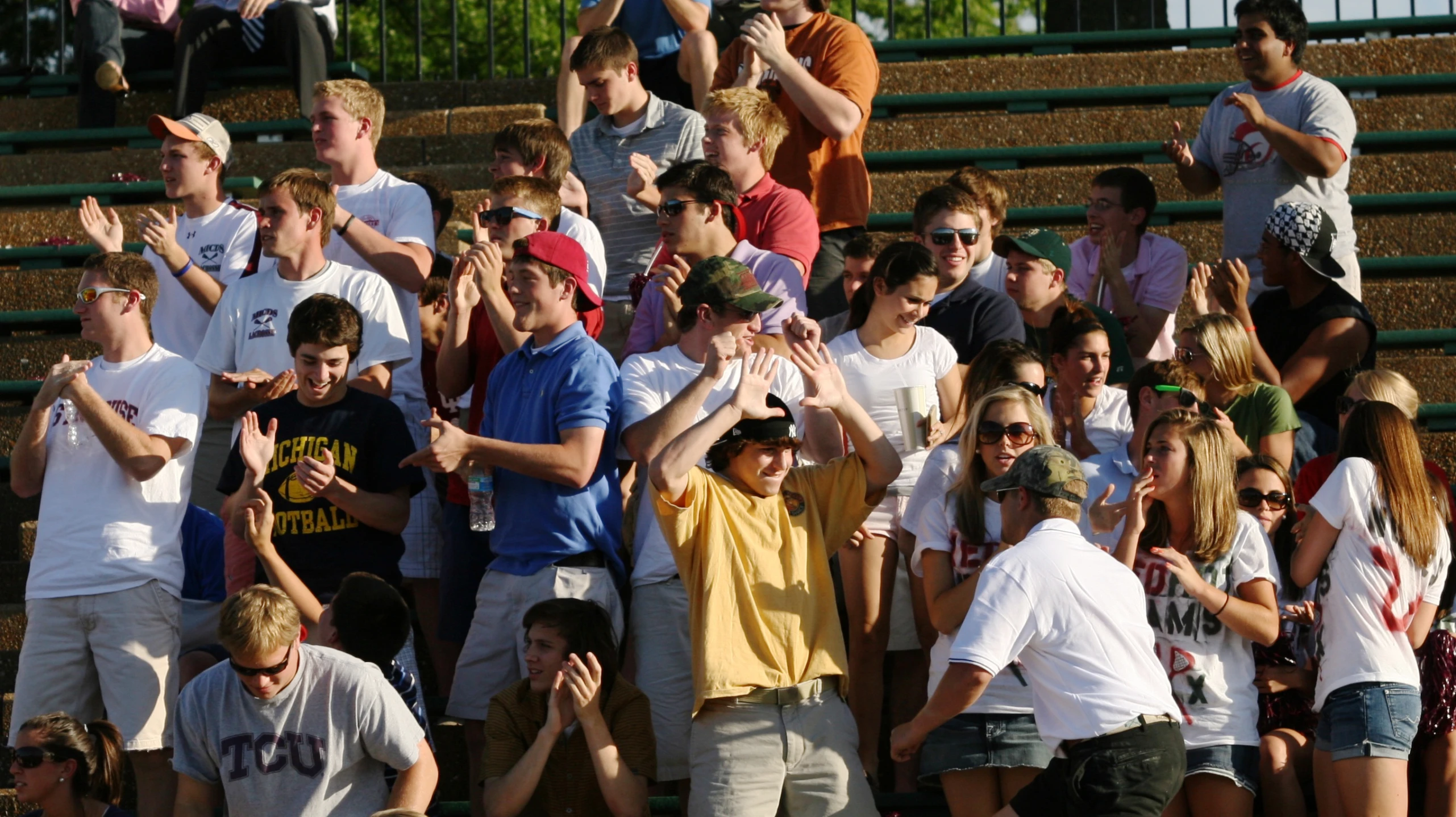 group of people with their hands up standing in front of a bleachers watching