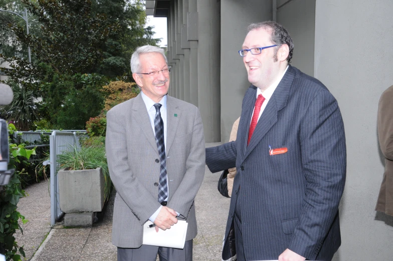 two men standing in suits and ties talking