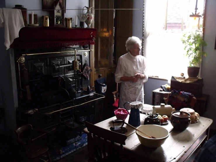 a woman stands in her kitchen, holding a glass