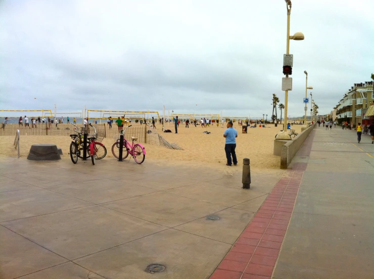 people are walking on the beach with bicycles
