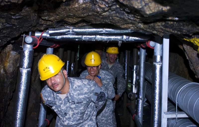 soldiers stand in a small tunnel that holds pipe works