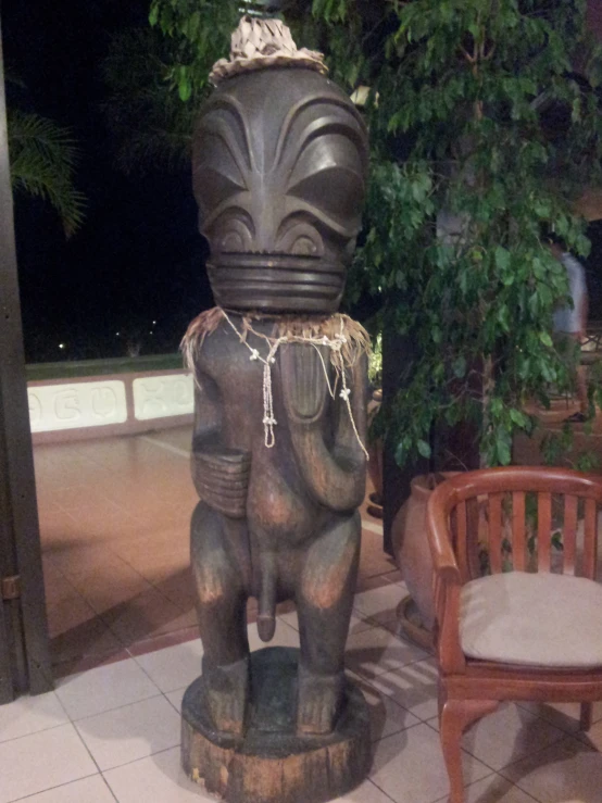 a wooden chair next to a pot with an elephant head on it