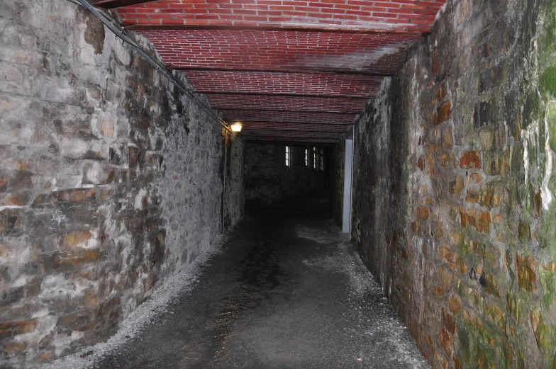 a stone tunnel is next to a brick wall