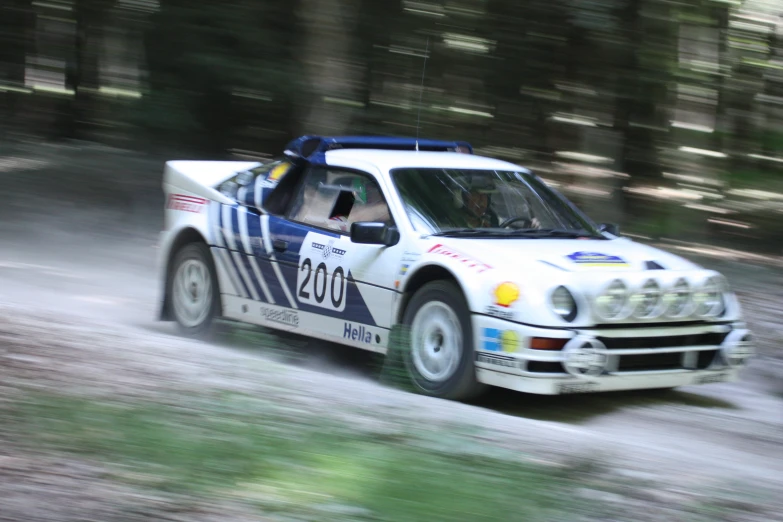 a white and blue race car traveling down a wooded track