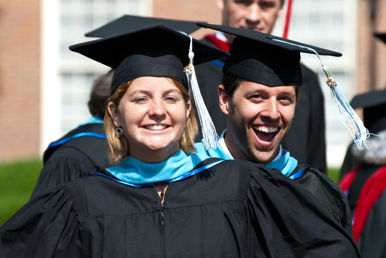 a couple of graduates standing together outside on graduation