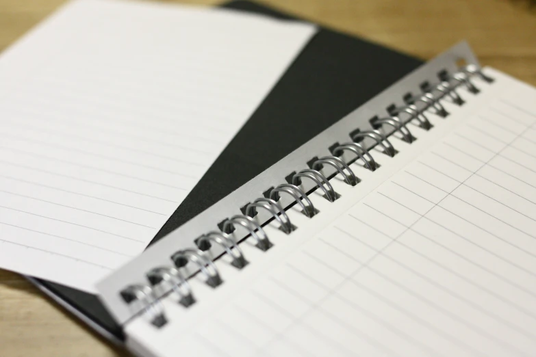 a note pad sits on a table, next to an empty notebook