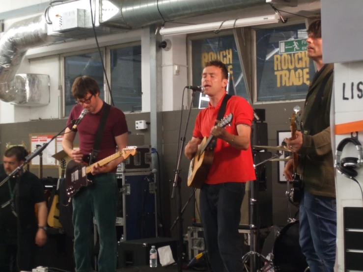 several men are playing guitar and singing in front of a microphone