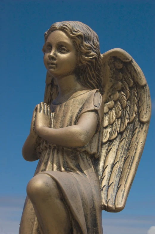 an antique gold statue has angel wings and a hand
