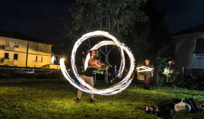 people are standing around in a backyard with their hula hoop lit by fire