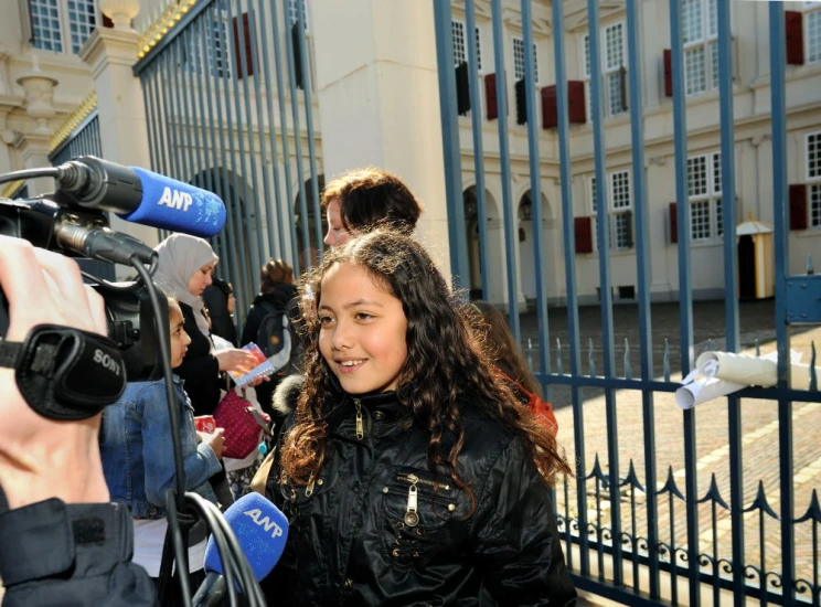 young woman is outside being interviewed by cameras
