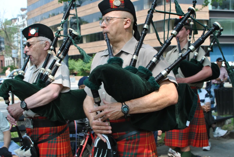 the men in kilts are playing their bagpipes