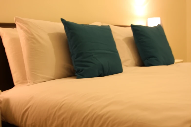 a bed with three blue and white pillows