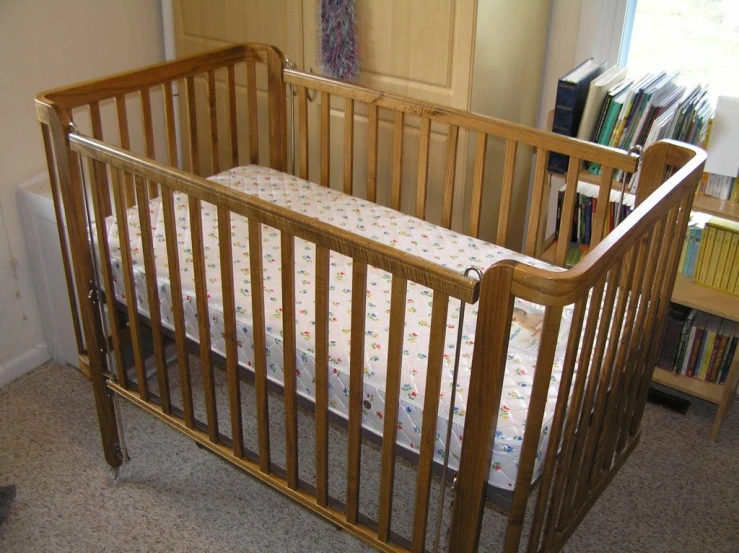 an empty crib in a home next to a bookshelf