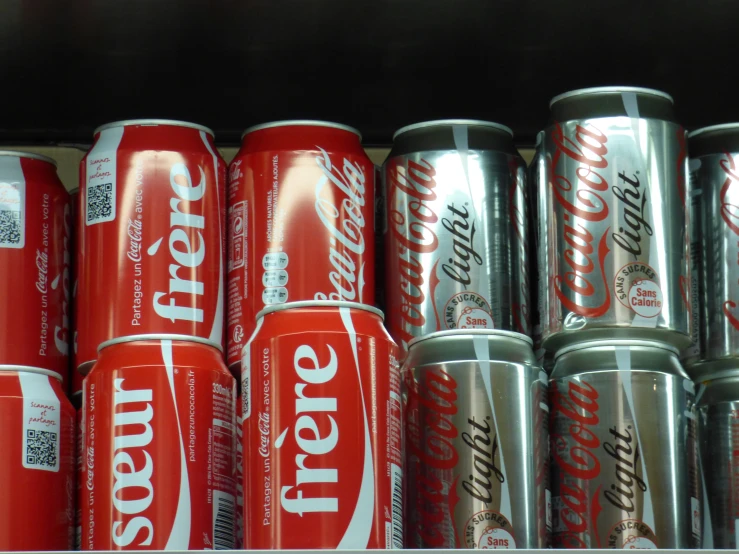 a shelf filled with cans of coca - cola