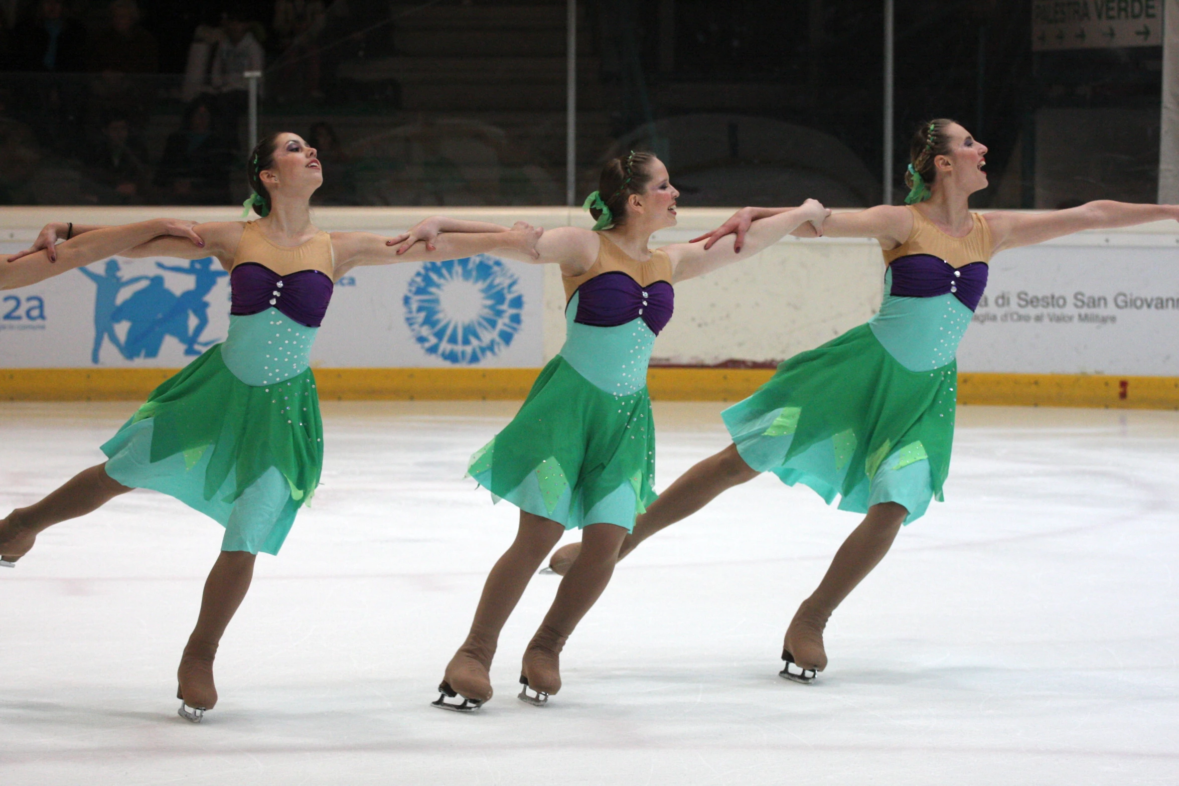 three female figure skating on an ice rink