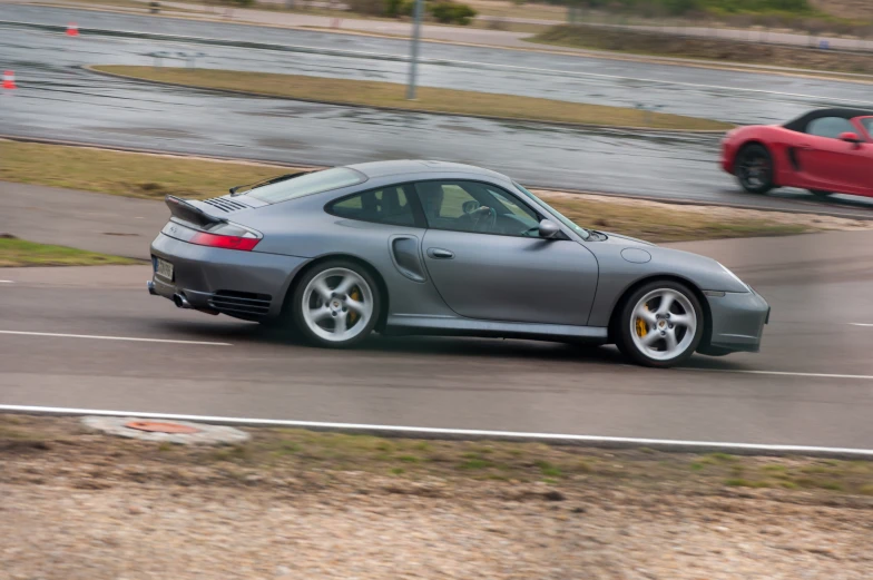 the porsche sports car is driving along the road