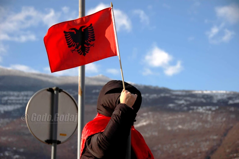 the girl is standing in front of a flag and holding a pole