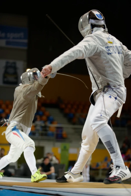 two men in fencing attire one of the fencing fence has an object to put on the back