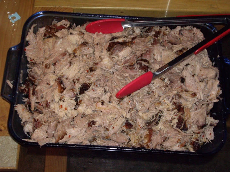 the homemade dish contains meat in it with red spoons