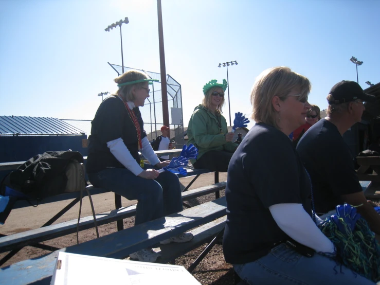 people sitting on a bench while wearing hats and scarves