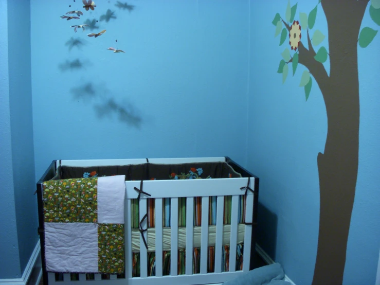 a crib is decorated with colorful wallpaper and tree decal