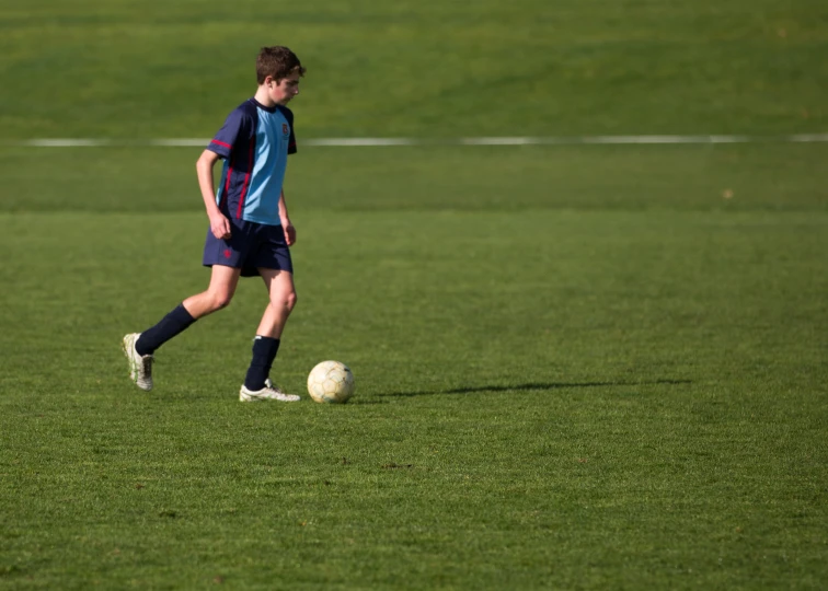 a boy standing next to a soccer ball on top of a field