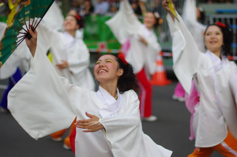 woman wearing a white dress dancing with japanese umbrellas