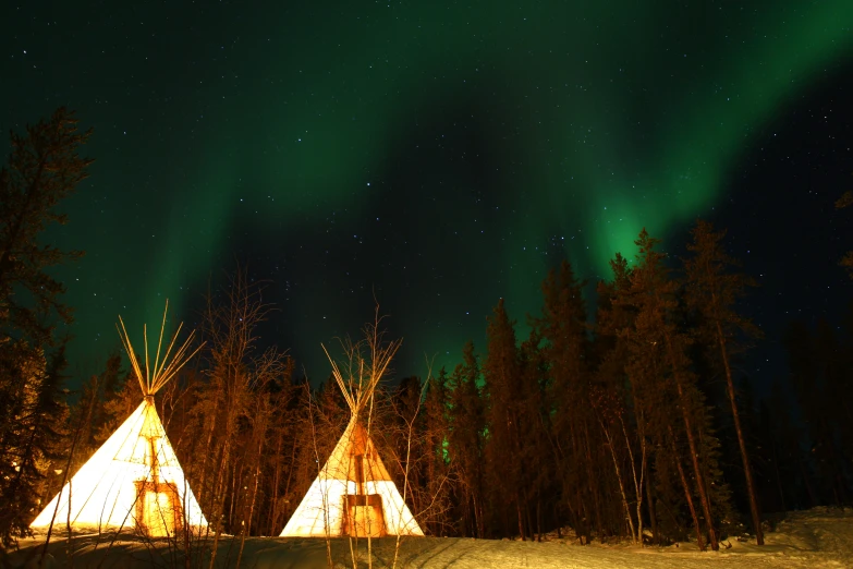 a group of teepees with aurora lights in the background
