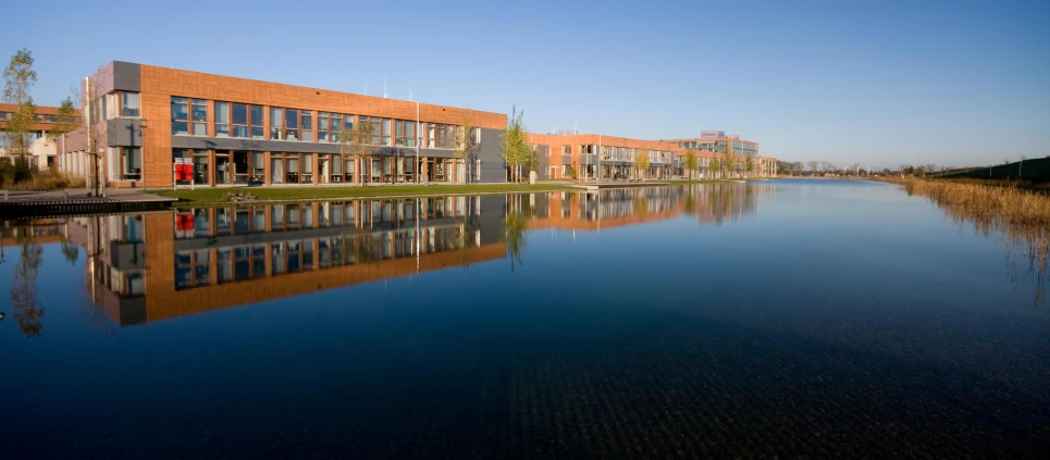 building next to water reflecting buildings with trees