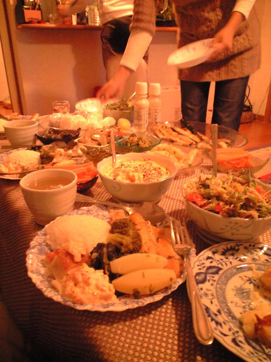 people stand around an array of plates of food