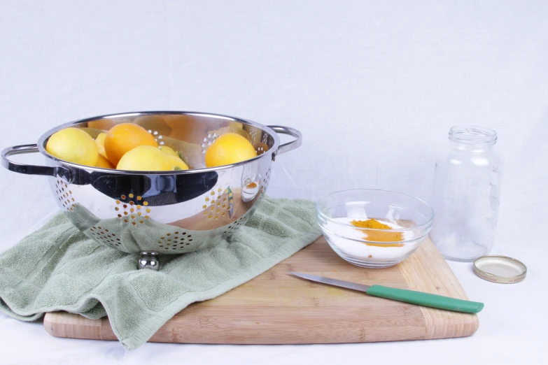 this is a steel bowl with lemons inside on a wood board