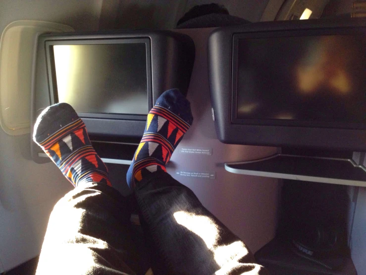 a person wearing socks with stripes on them sits in an airplane