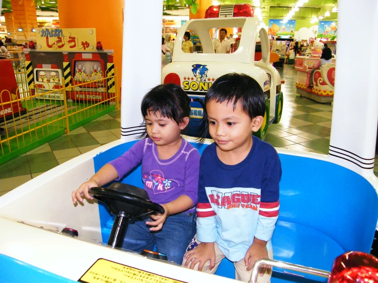 two young children sit in a toy car