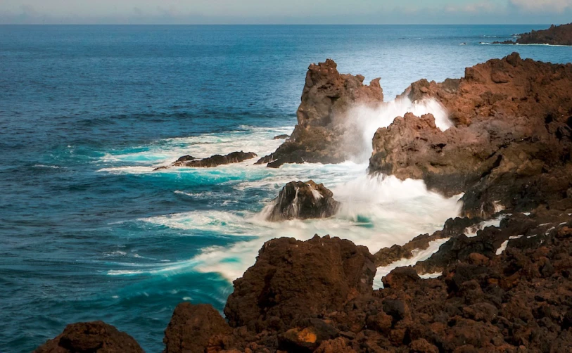 there are waves crashing into the rocks at the shore