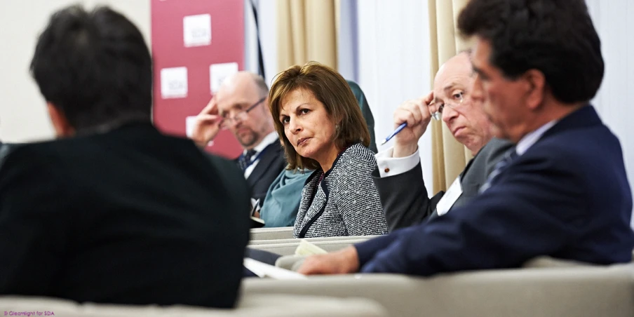 two people sit at a table while one man looks on