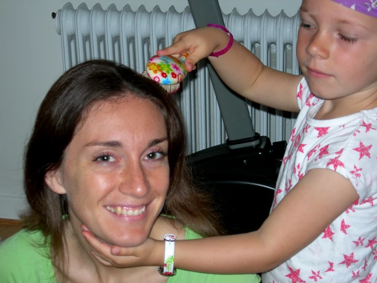 a woman is blowdrying a small girl's hair