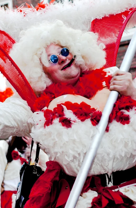 a man in costume poses as he wears his face with a red and white feathered hat