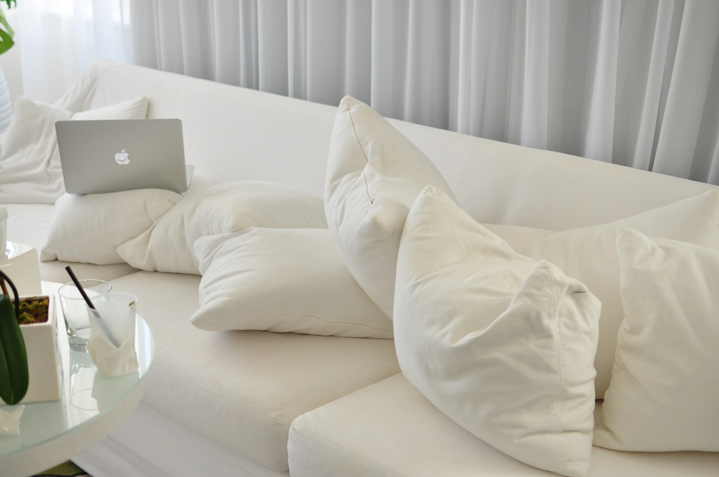 a white sofa with several pillows next to it and a lap top