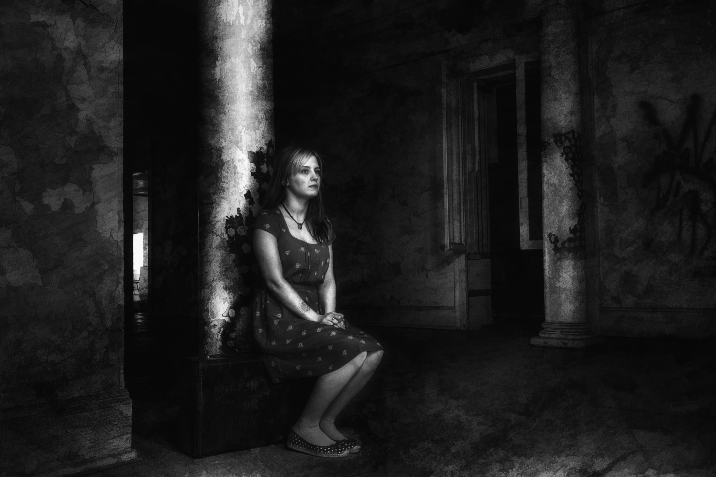 a woman sitting against the wall in an old building